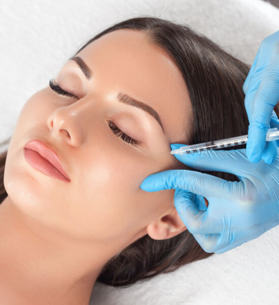 Close-up of a woman receiving a cosmetic injectable treatment near the eye area, administered by a professional wearing blue gloves