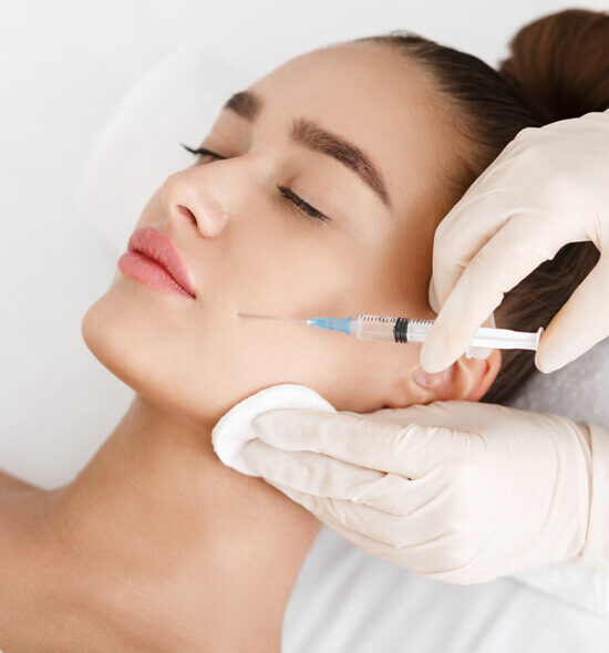 Close-up of a woman receiving a facial injection from a medical professional wearing gloves, targeting the cheek area for cosmetic enhancement.
