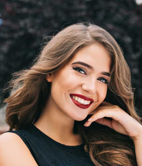 Woman smiling looking at camera with her hand touching her face