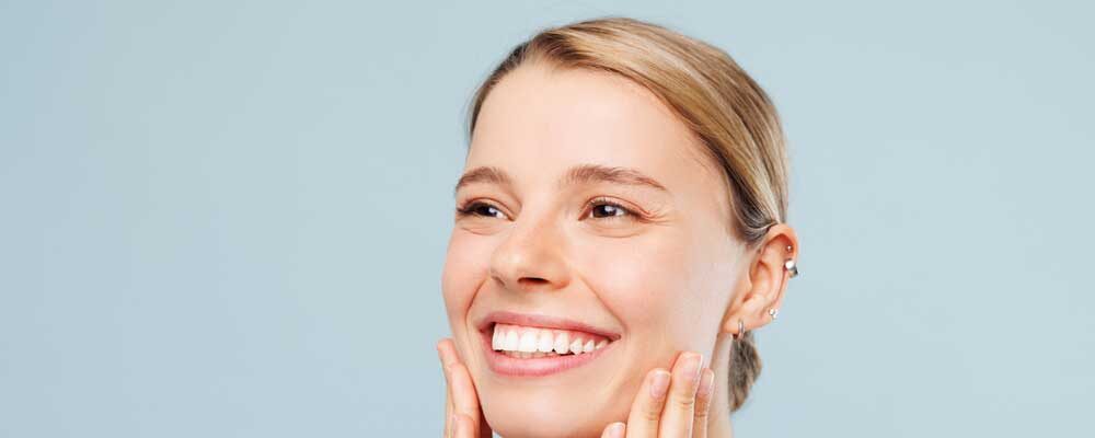 Close of woman smiling and holding her face with both hands