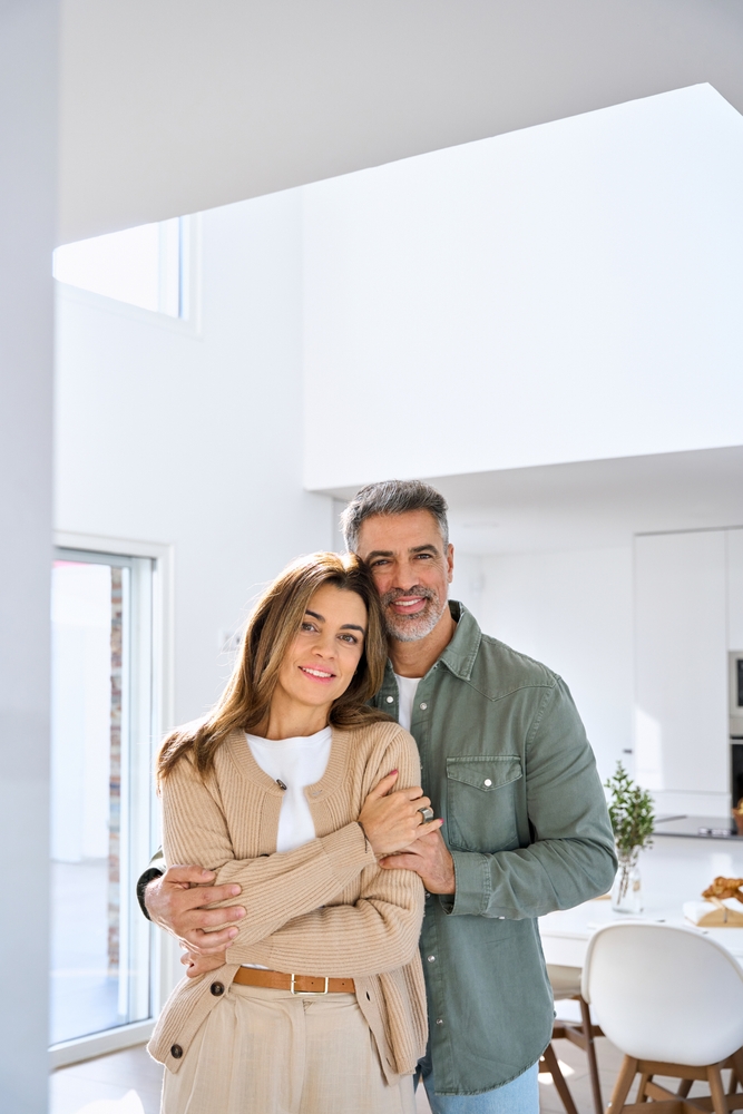 Smiling middle-aged couple embracing in a bright modern home, looking happy and relaxed together